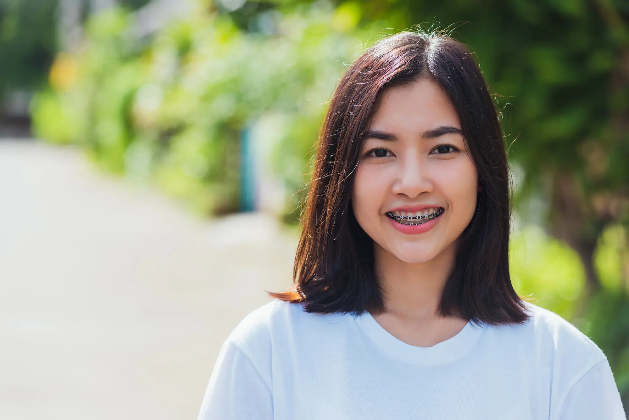 A confident woman with brown hair smiles, highlighting the benefits of adult orthodontics at Koerich Orthodontics in Charlotte, Indian Trail and Monroe, NC.