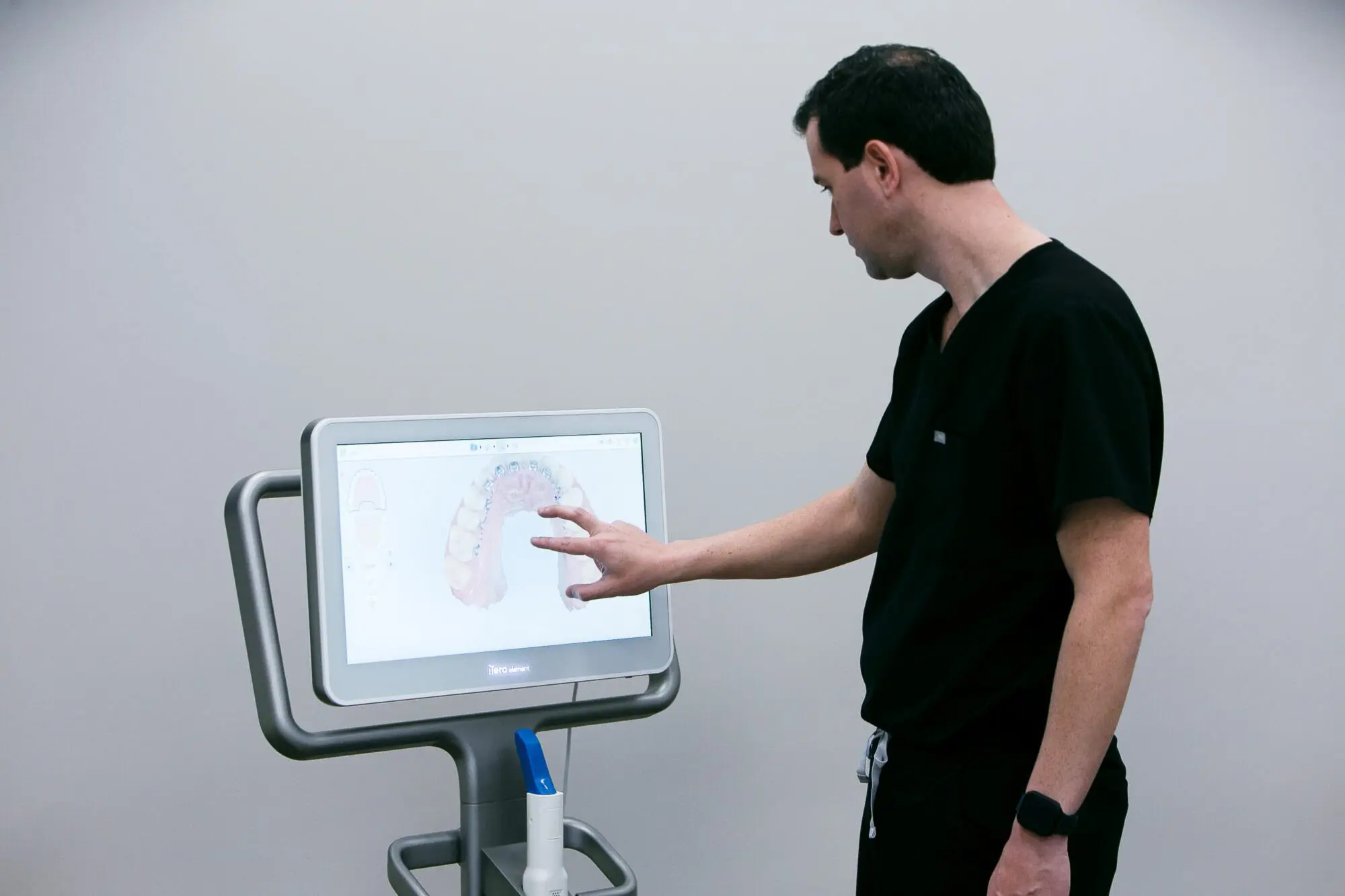 A person in black scrubs interacts with a touchscreen displaying dental imagery at Koerich Orthodontics in Monroe NC