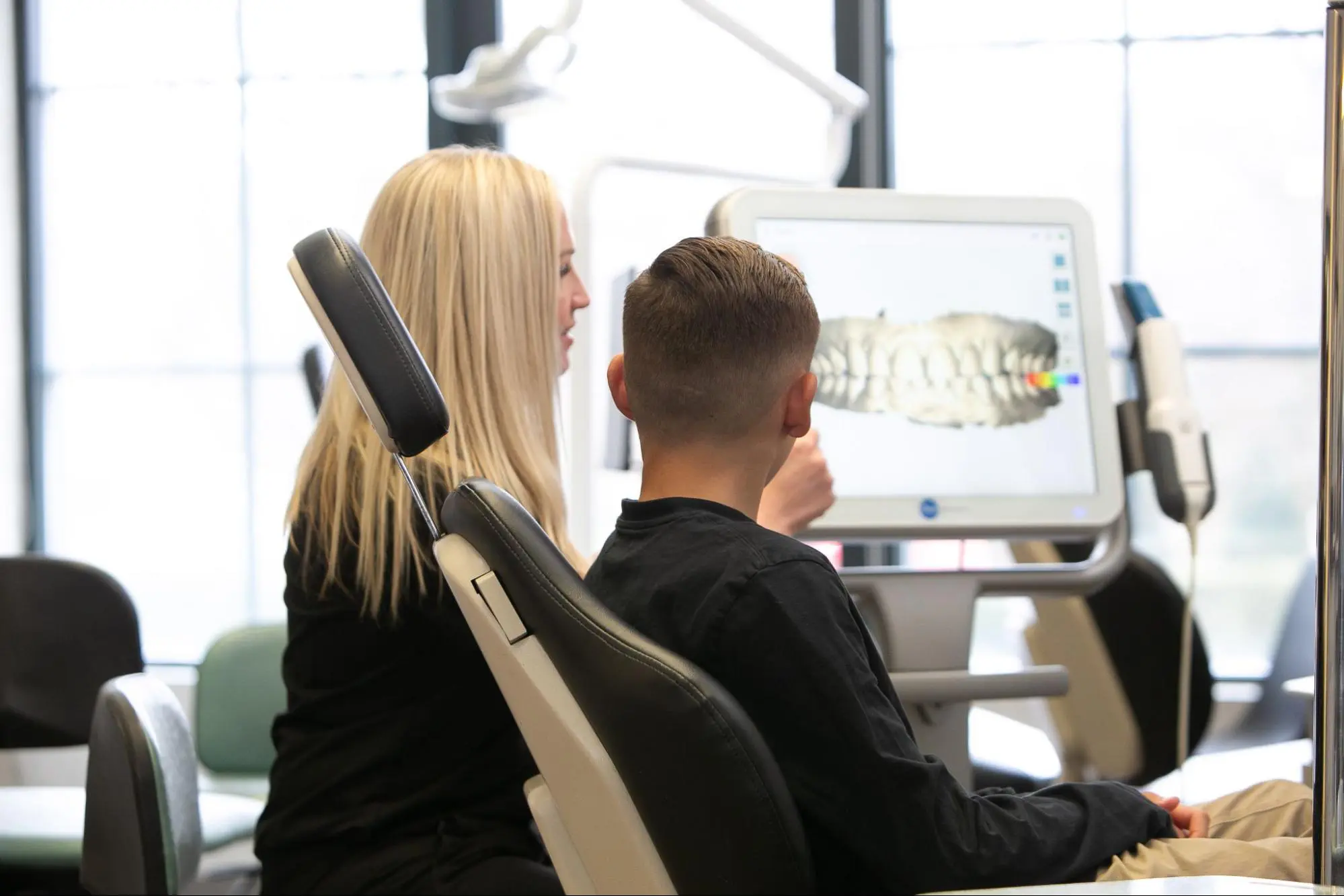 At Koerich Orthodontics, a dental professional reviews a digital teeth model with a patient on a computer screen, ensuring personalized care in their modern office setting in Monroe NC