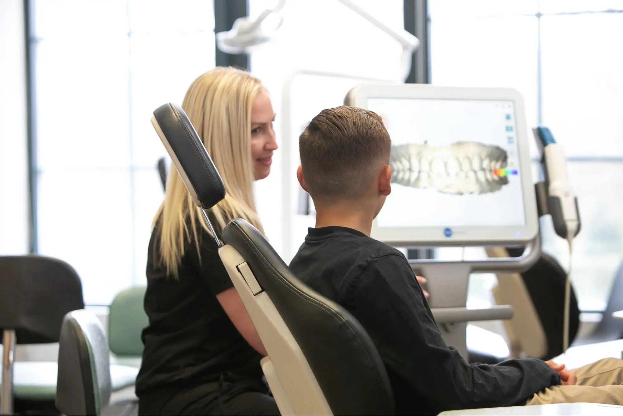 At Koerich Orthodontics, a friendly specialist discusses a digital dental scan with a young patient, both seated comfortably in front of a monitor displaying teeth in Indian Trail NC
