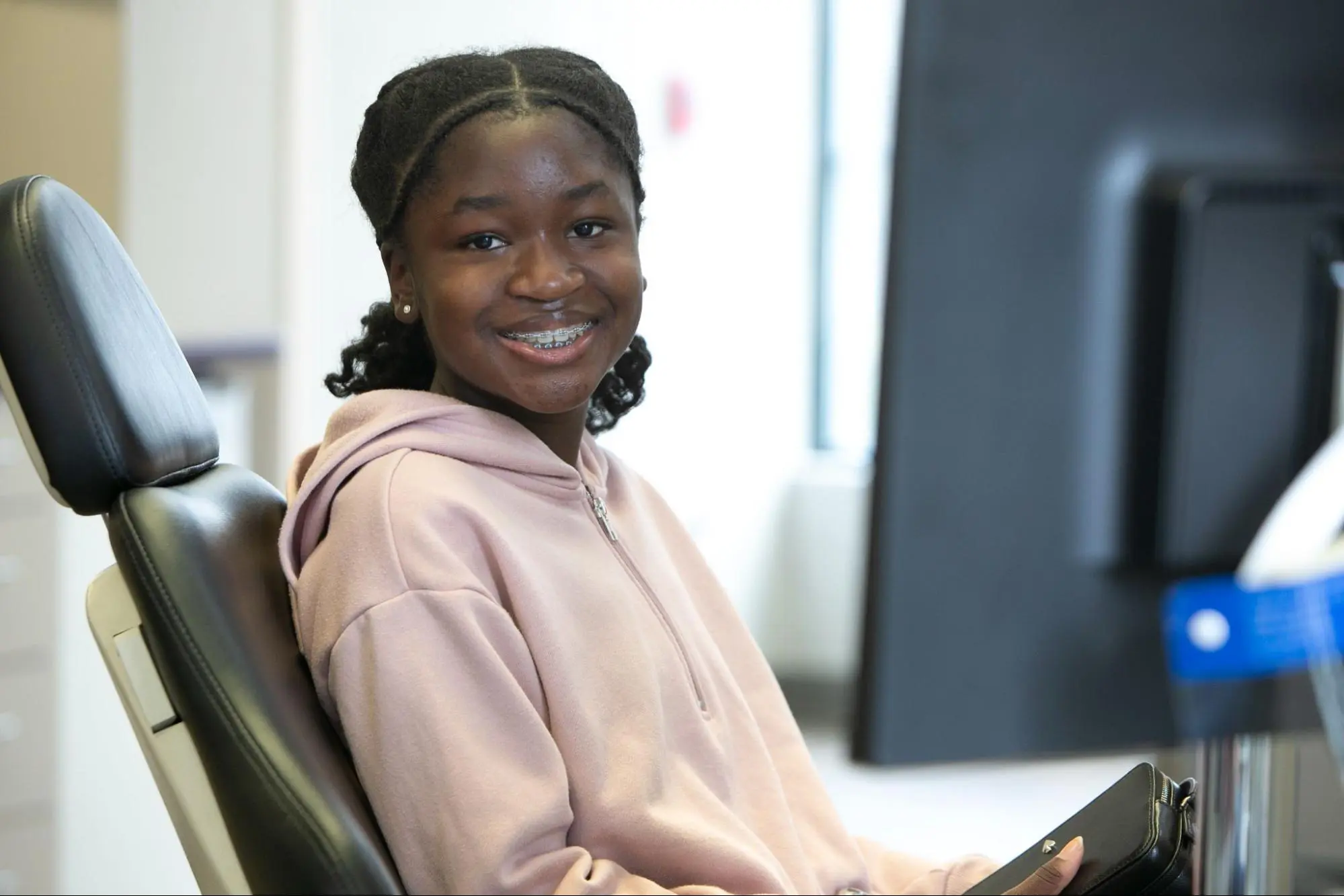 A young person with long brown hair and braces, representing the benefits of adult orthodontics at Koerich Orthodontics in Charlotte, Indian Trail and Monroe, NC.