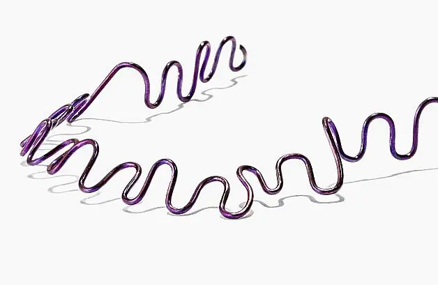 Purple wavy metallic wire, reminiscent of lingual braces, set against a crisp white background in Indian Trail, NC