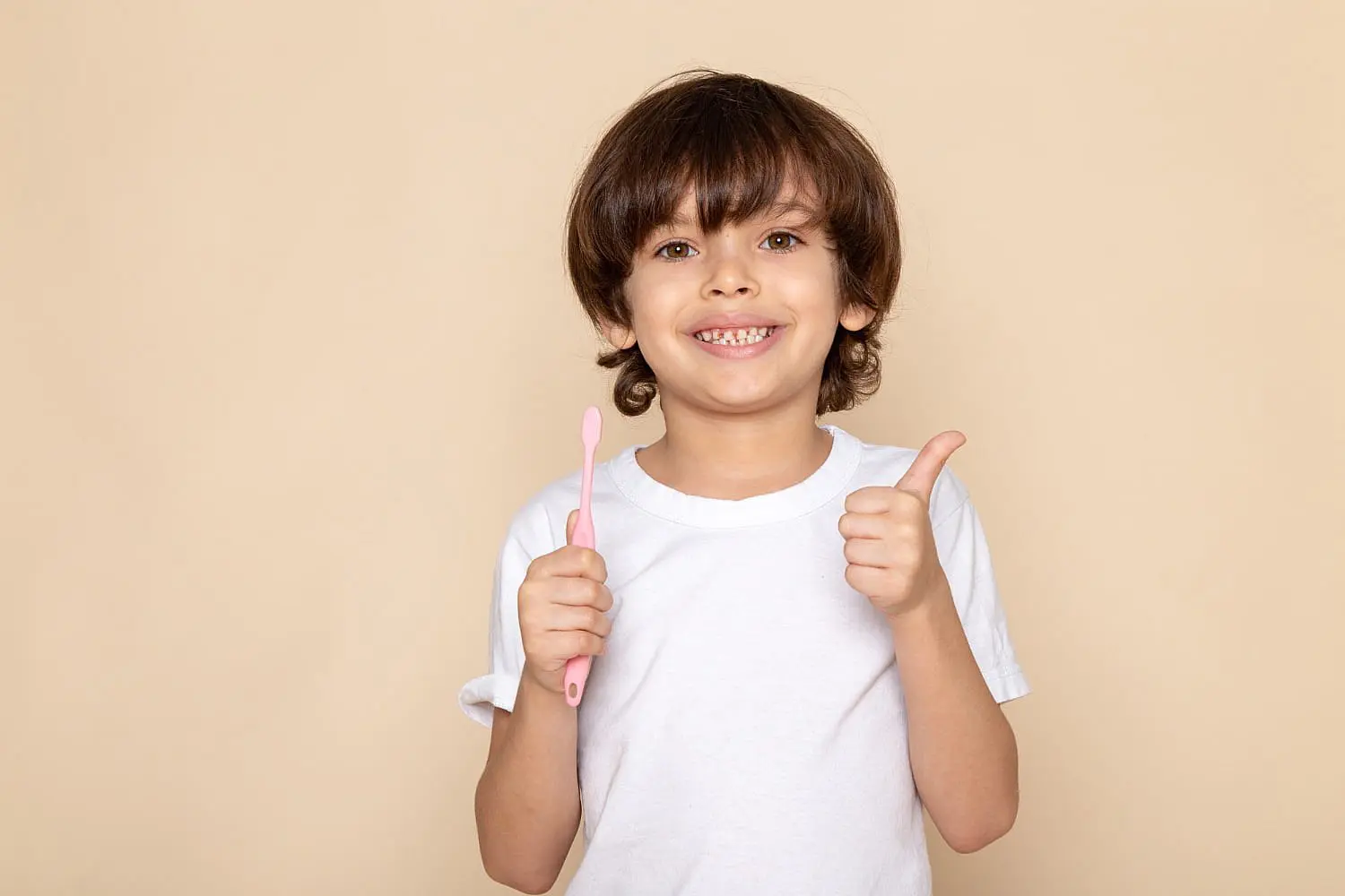 A smiling child gives a thumbs up and holds a pink toothbrush show common orthodontic issues with her teeth need children’s orthodontist for begin treatment dental in Charlotte, Indian Trail and Monroe, NC.