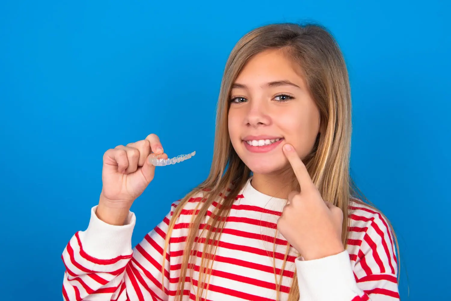 A child hold clear aligners from top-rated children’s orthodontist in Charlotte, Indian Trail and Monroe, NC.