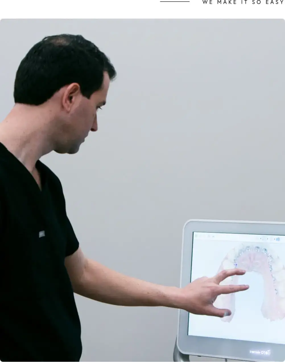 At Koerich Orthodontics in Charlotte, Indian Trail, or Monroe NC, a staff member in black scrubs points to digital scans on a monitor set against a light-colored wall.